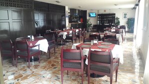 A restaurant with multiple tables and chairs, a tiled floor, and a television on the wall. - Hotel Montreal (Mexico City)