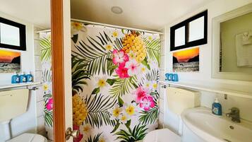 A bathroom with two white sinks, a toilet, and a shower curtain with a tropical floral pattern.