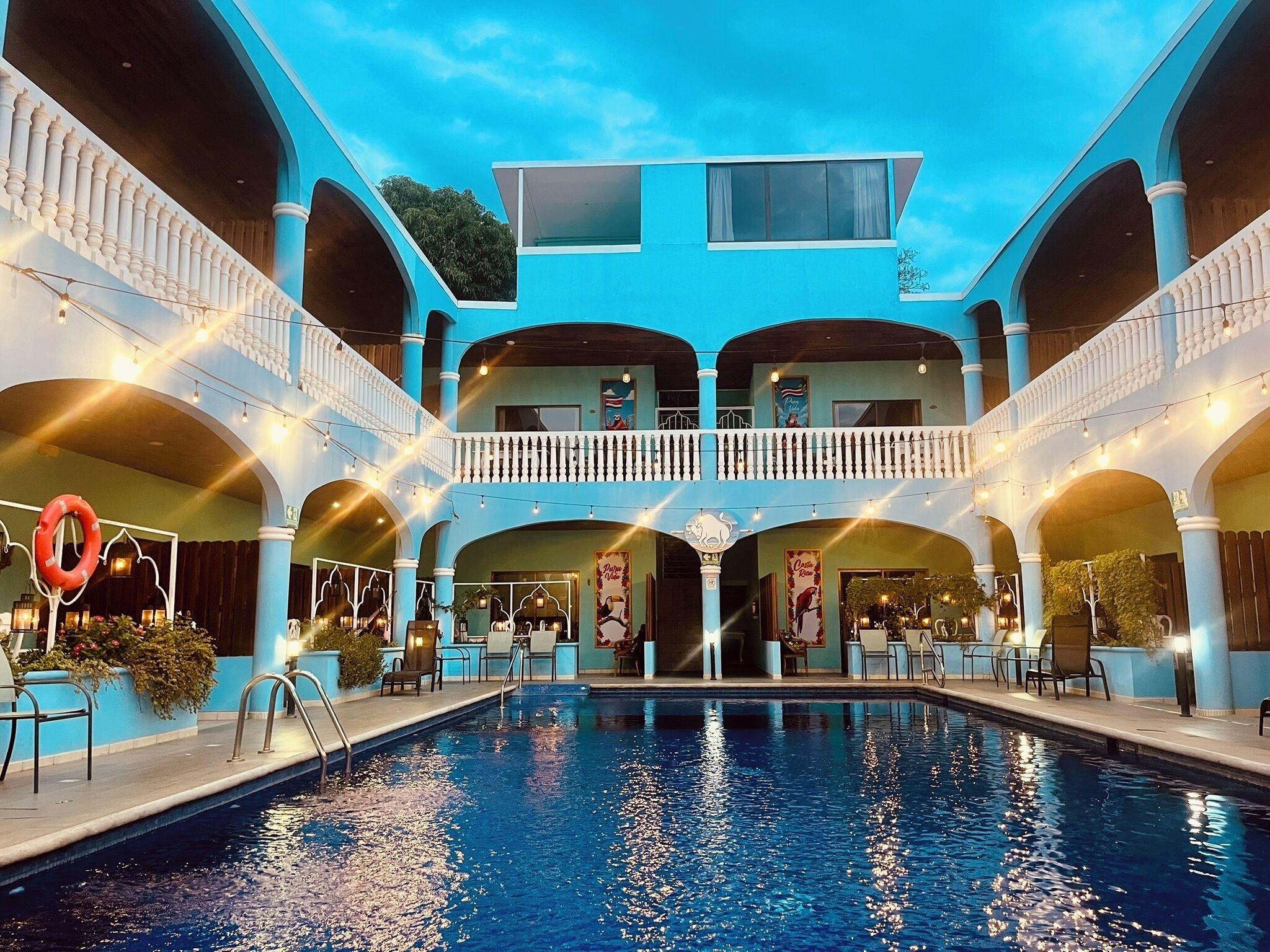 A pool area with a two-story building, outdoor seating, and a lifebuoy.