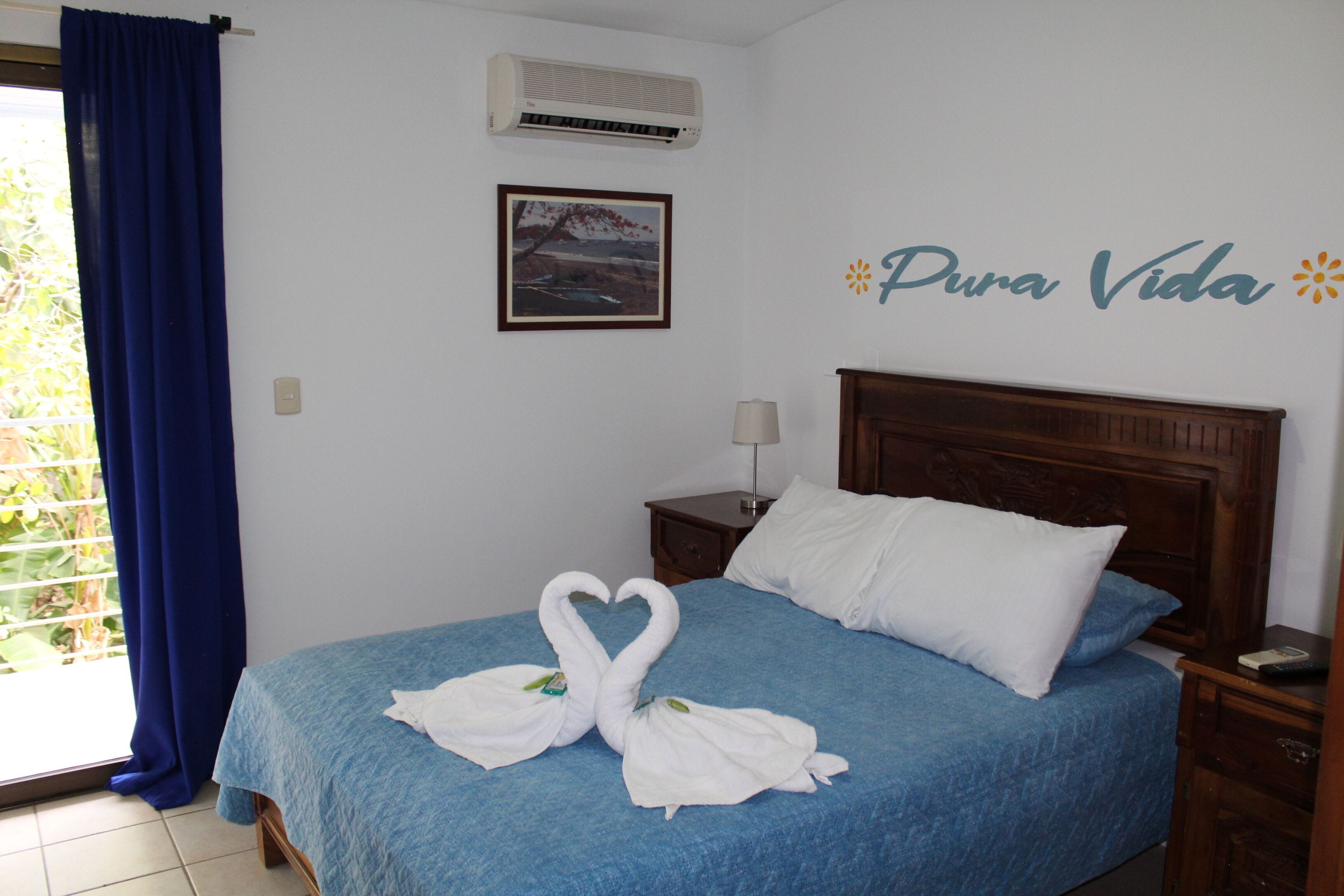 A hotel room with a bed, a nightstand, a lamp, and a wall decoration.