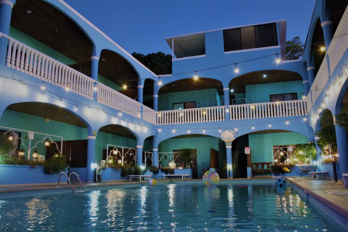 Un immeuble à plusieurs étages doté d’une piscine, de balcons et de guirlandes lumineuses.