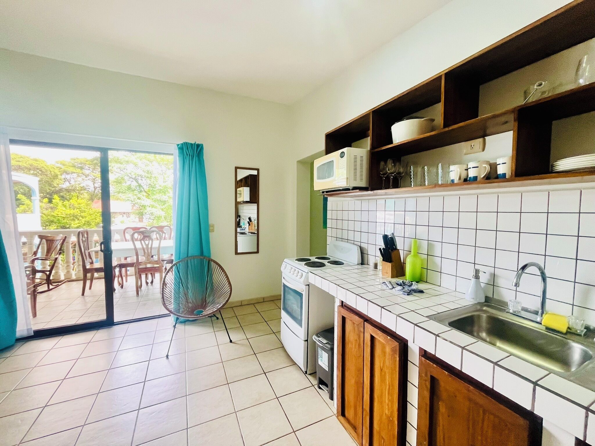 A kitchen with a stove, microwave, sink, and a dining area with chairs and a table.