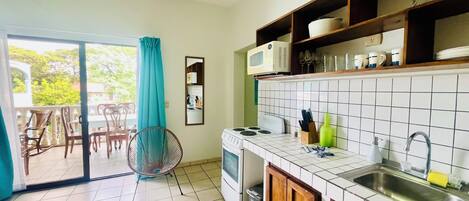 A kitchen with a stove, microwave, sink, and a dining area with chairs and a table.