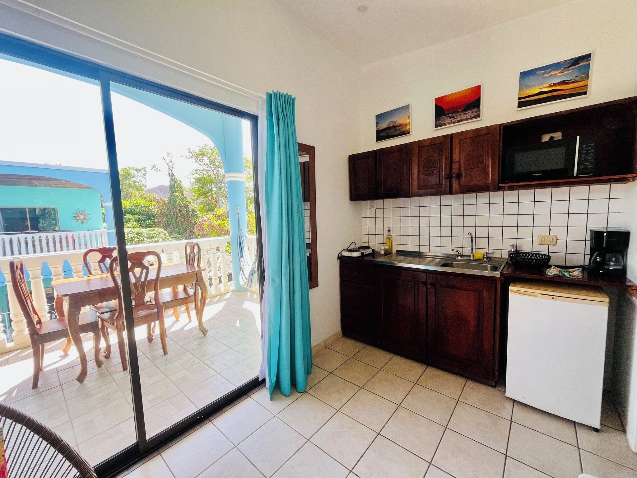 Una cocina con comedor, vista a través de un ventanal y un balcón con barandilla azul.
