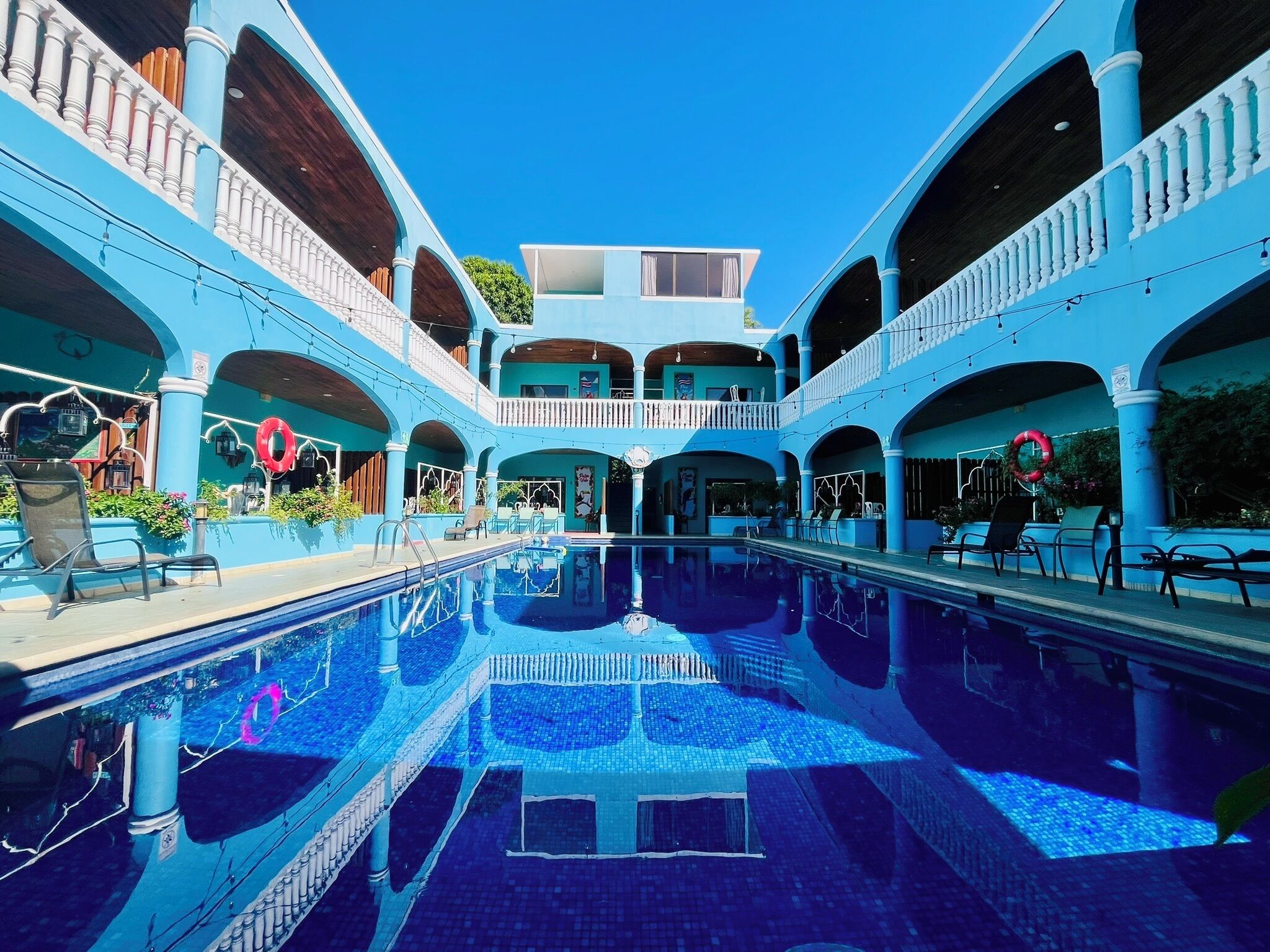 Una piscina con reflejos, rodeada por una estructura de varios niveles con balcones.