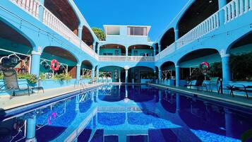 Una piscina con reflejos, rodeada por una estructura de varios niveles con balcones.