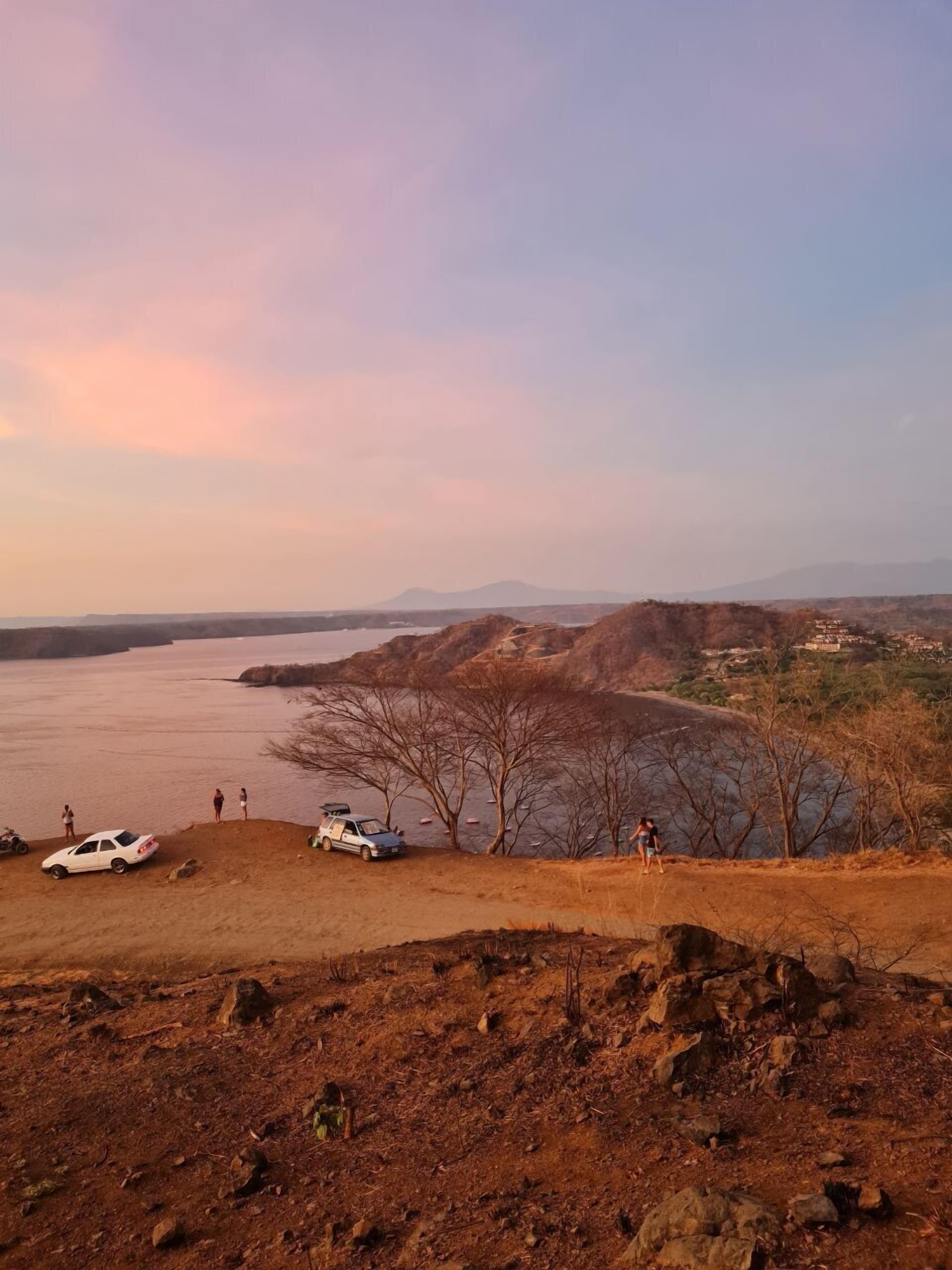 A scenic overlook with a view of a body of water, rocky terrain, and distant hills.