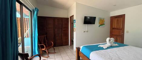 A hotel room with a bed, a television, a wooden wardrobe, and a rocking chair.