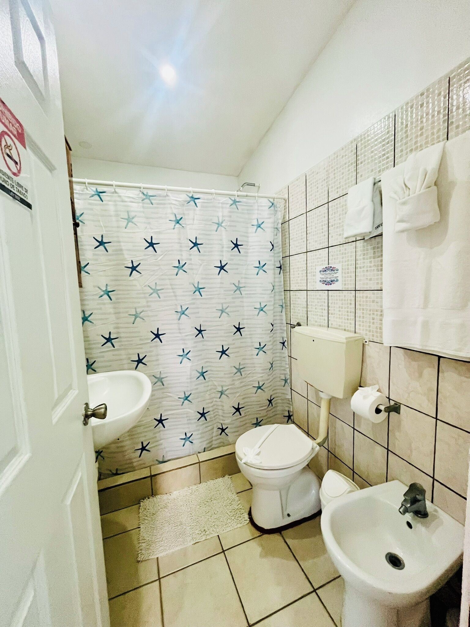 Een kleine badkamer met een douchegordijn met stermotieven, een toilet, een wastafel en een handdoekhouder.