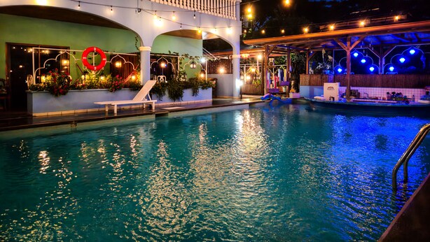 Zona de piscina con terraza cubierta, sillas de descanso y un adorno de flotador.