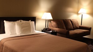 Ein Hotelzimmer mit einem Bett, einem Sofa, zwei Nachttischlampen und einem Nachttisch mit einer Uhr.