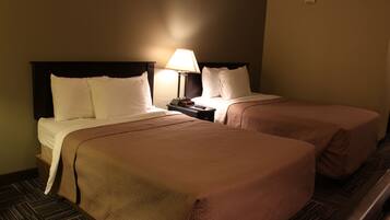 A hotel room with two beds, a nightstand with a lamp, and a carpeted floor.