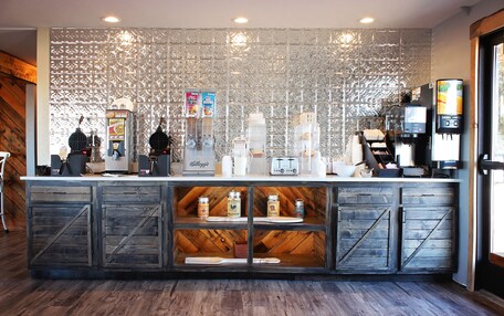 A coffee shop counter with a rustic design, including wooden cabinets and a decorative metal wall.