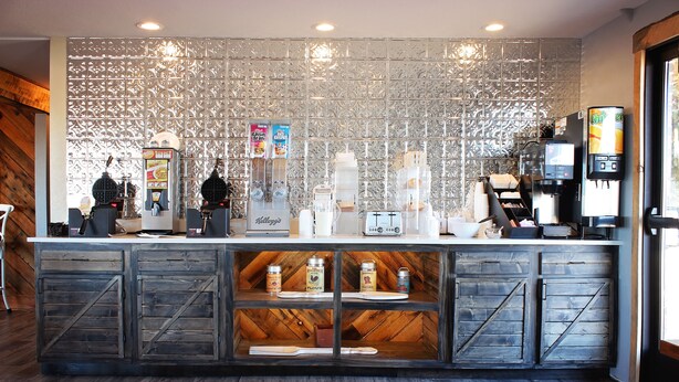 Ein Thekenbereich eines Cafés mit rustikalem Design, darunter Holzschränke und eine dekorative Metallwand.