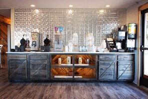 A coffee shop counter with a rustic design, including wooden cabinets and a decorative metal wall.