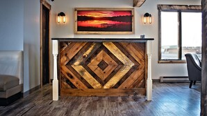 Ein Empfangsschalter mit Holz-Zinkendekor, ein Sonnenuntergangsgemälde darüber und ein Blick ins Freie durch ein Fenster.