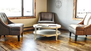 Ein Zimmer mit drei Sesseln, einem runden Tisch und einer Wanddekoration.