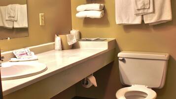 Un baño con lavamanos, inodoro y varias toallas colgadas en la pared.
