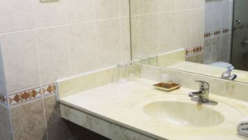 Un baño con lavabo, espejo y paredes con azulejos.