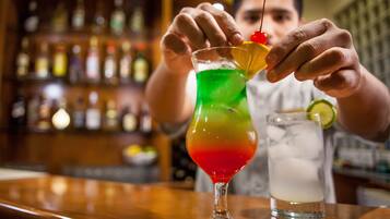 A bartender preparing a colorful cocktail with a lime garnish.