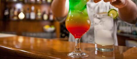A bartender preparing a colorful cocktail with a lime garnish.