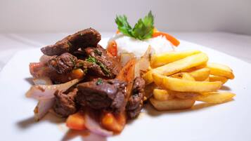 A plate with beef, rice, and French fries.