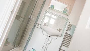 Ein Badezimmer mit Dusche, Waschbecken und Spiegel.