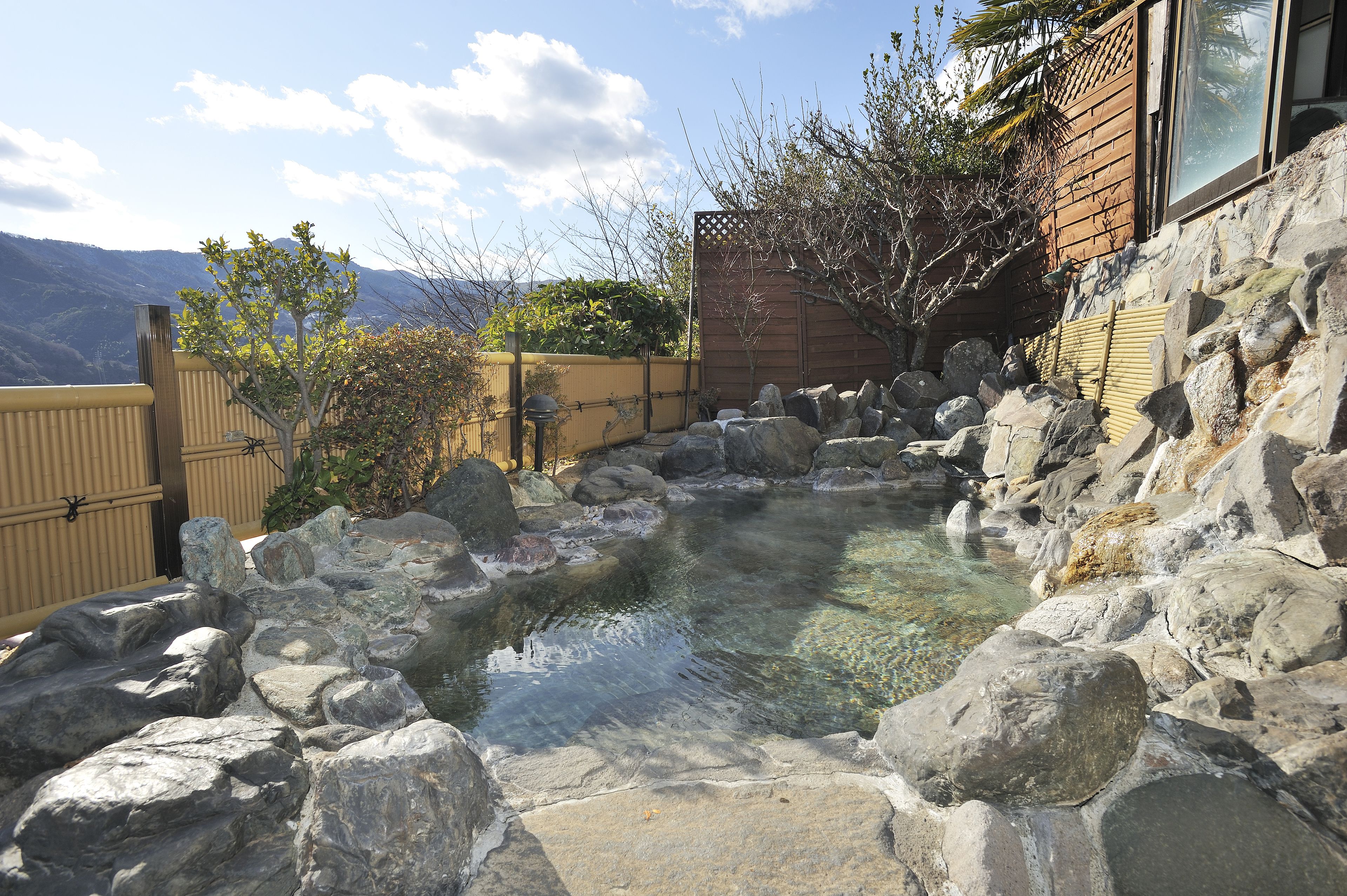 A hot spring surrounded by rocks and a wooden fence.