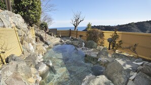 A traditional Japanese onsen with a clear hot spring surrounded by rocks and a wooden fence. - Hotel Chobo Sanso (Yugawara)