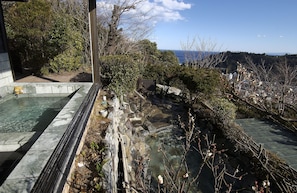A traditional Japanese onsen with stone baths, surrounded by natural scenery and a view of the sea. - Hotel Chobo Sanso (Yugawara)