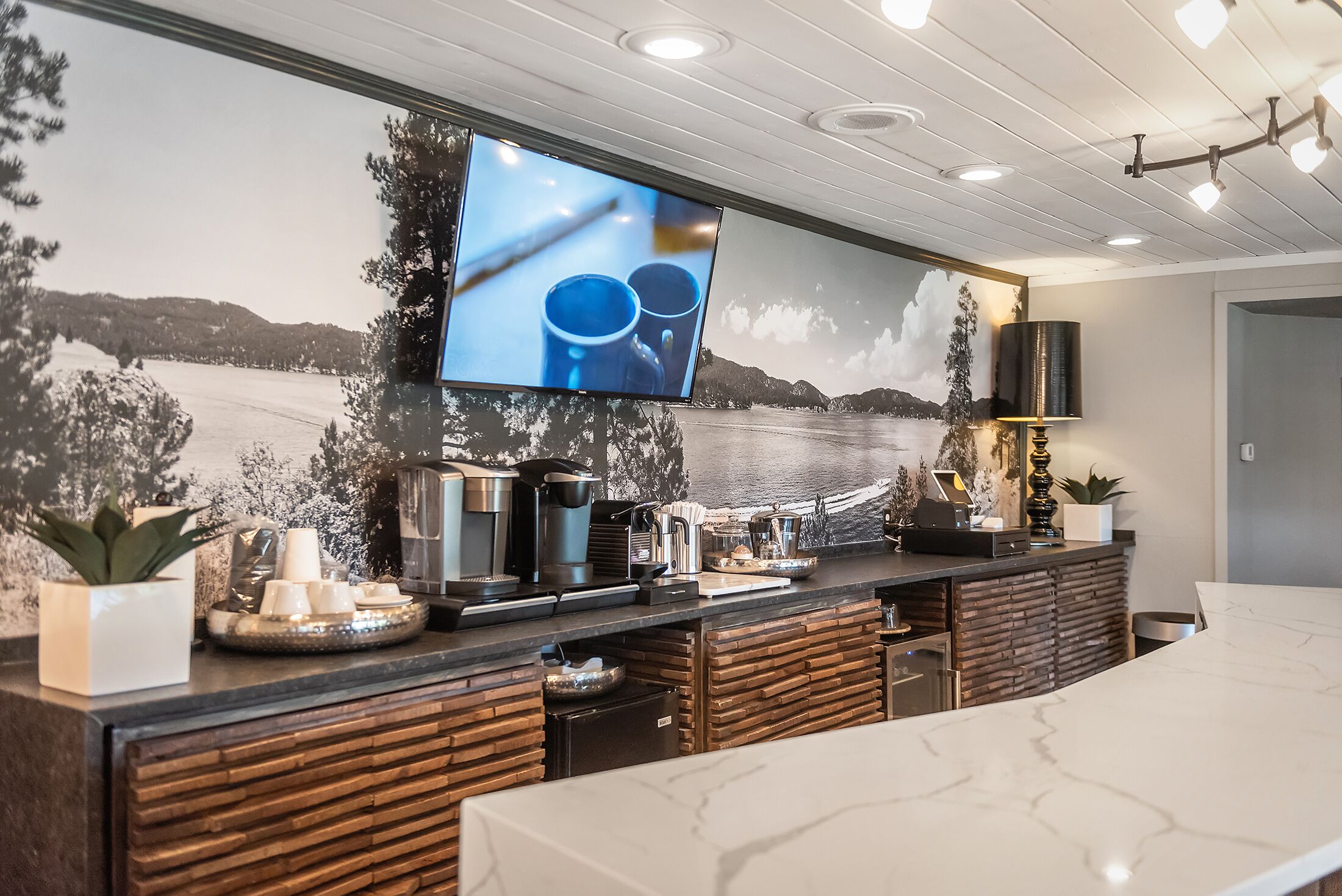 Una cocina moderna con un televisor grande, armarios de madera y encimera de mármol.