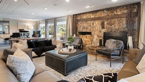 A modern living room with a stone fireplace, leather sofas, and a piano in the background. - Black Forest Inn Bed & Breakfast (Rapid City)