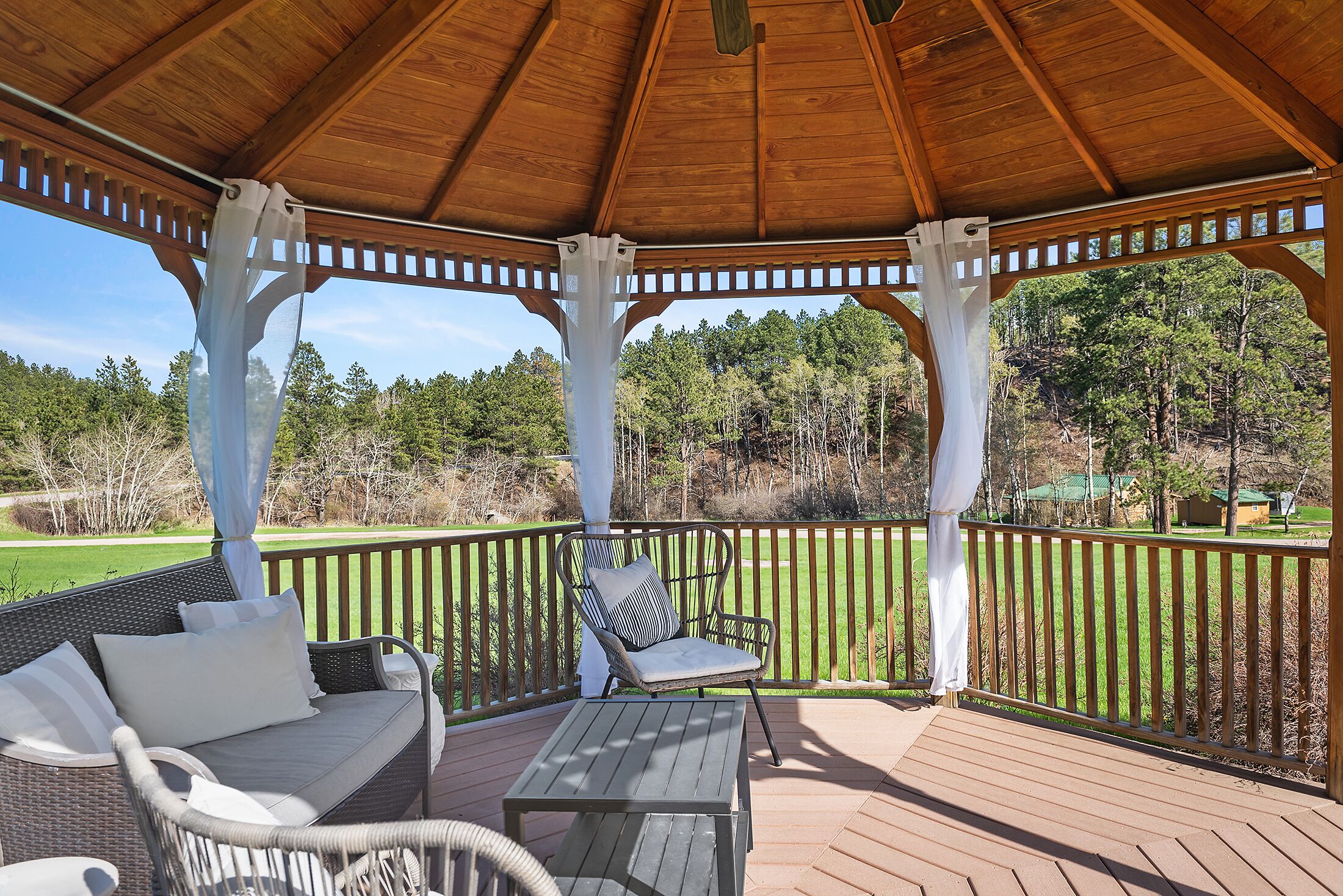 A covered outdoor seating area with wicker furniture and a wooden table.