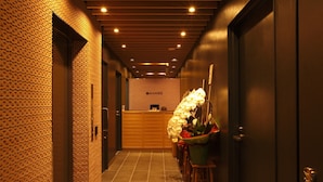 A hotel reception area with a reception desk, a wall with a patterned design, and a reception counter. - HOTEL AMANEK Ginza East (Tokyo)