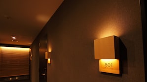 A hallway with a wall-mounted light fixture displaying the number 801. - HOTEL AMANEK Ginza East (Tokyo)