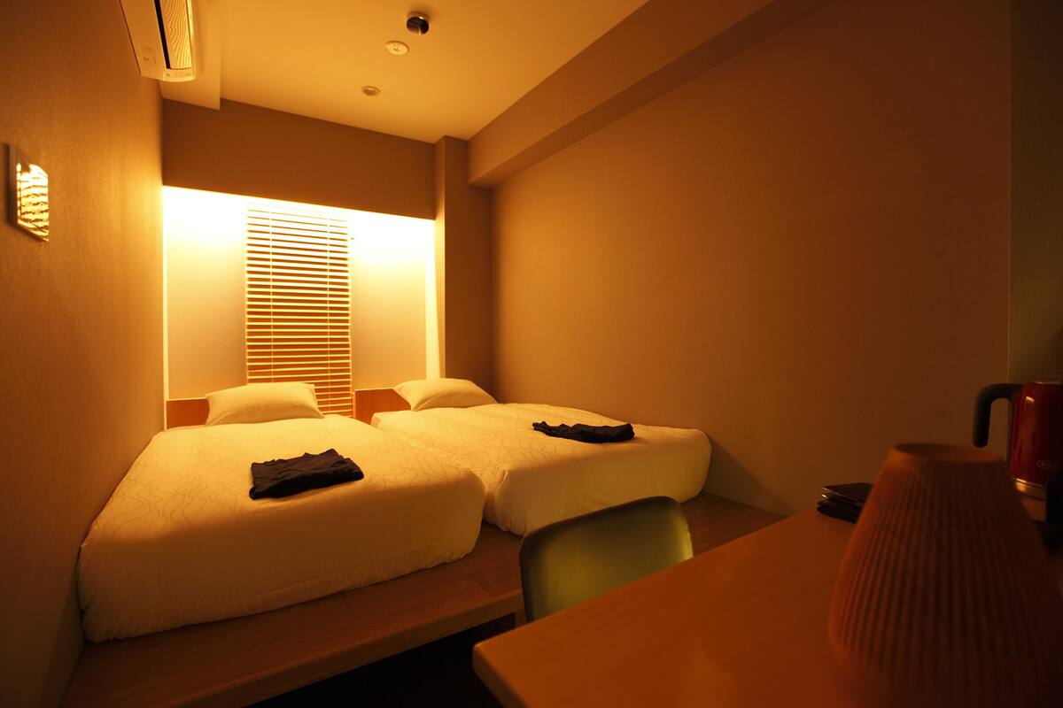 A hotel room with two beds, a desk, and a chair.