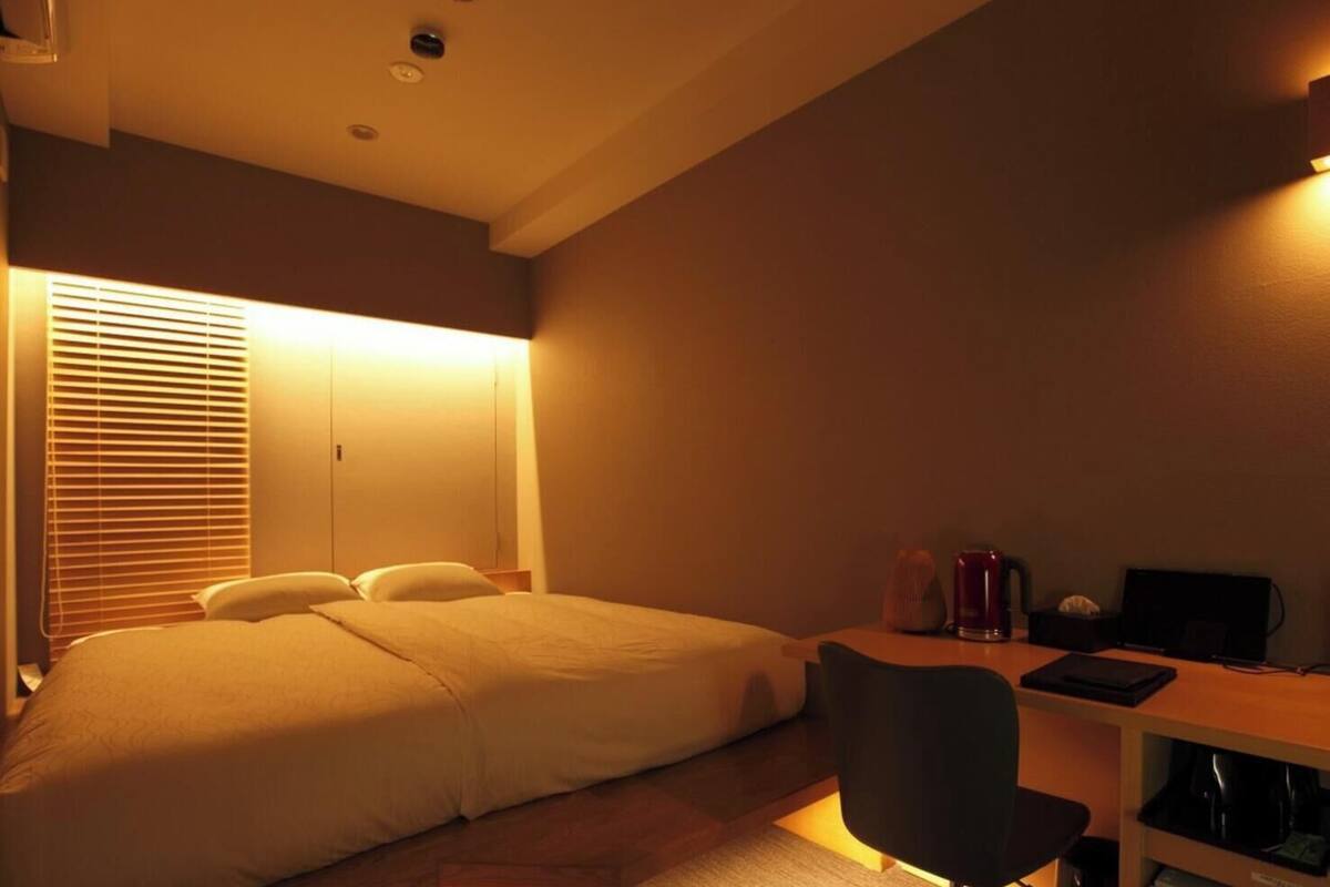 A bedroom with a bed, a desk, and a chair.