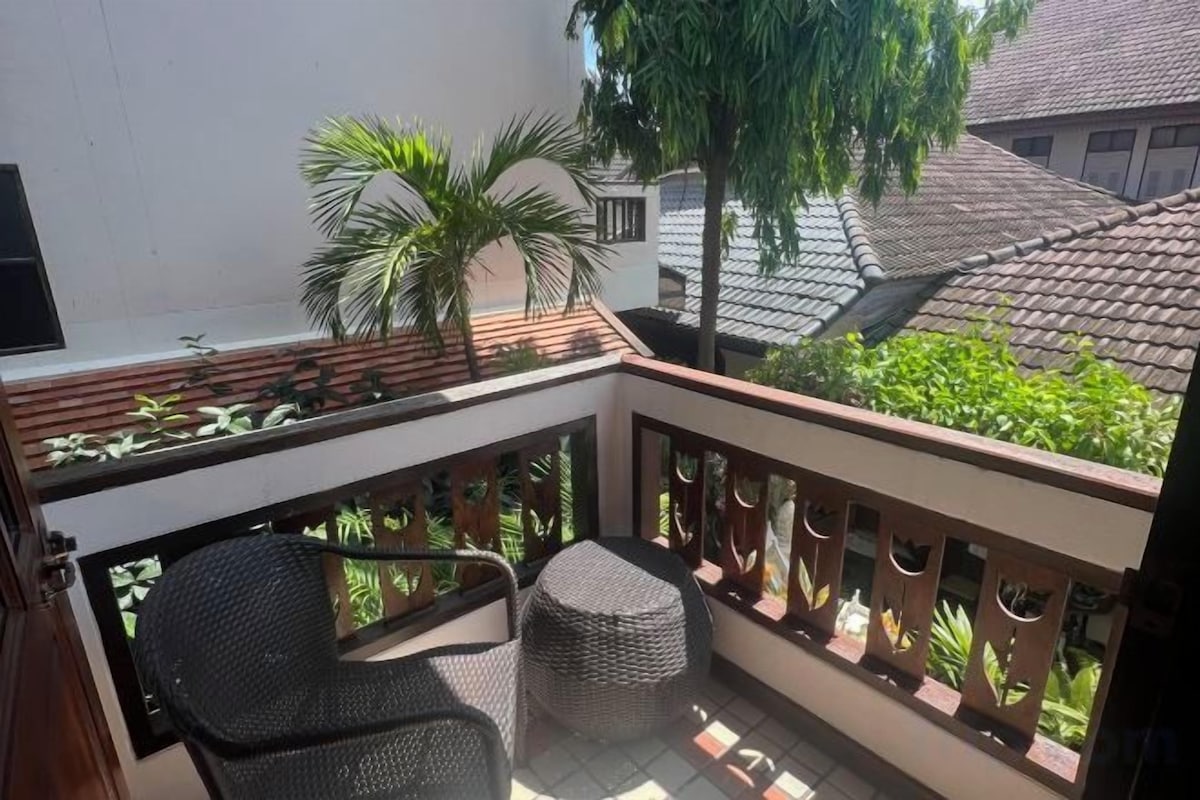 A balcony with a small table and two chairs, surrounded by a wooden railing.