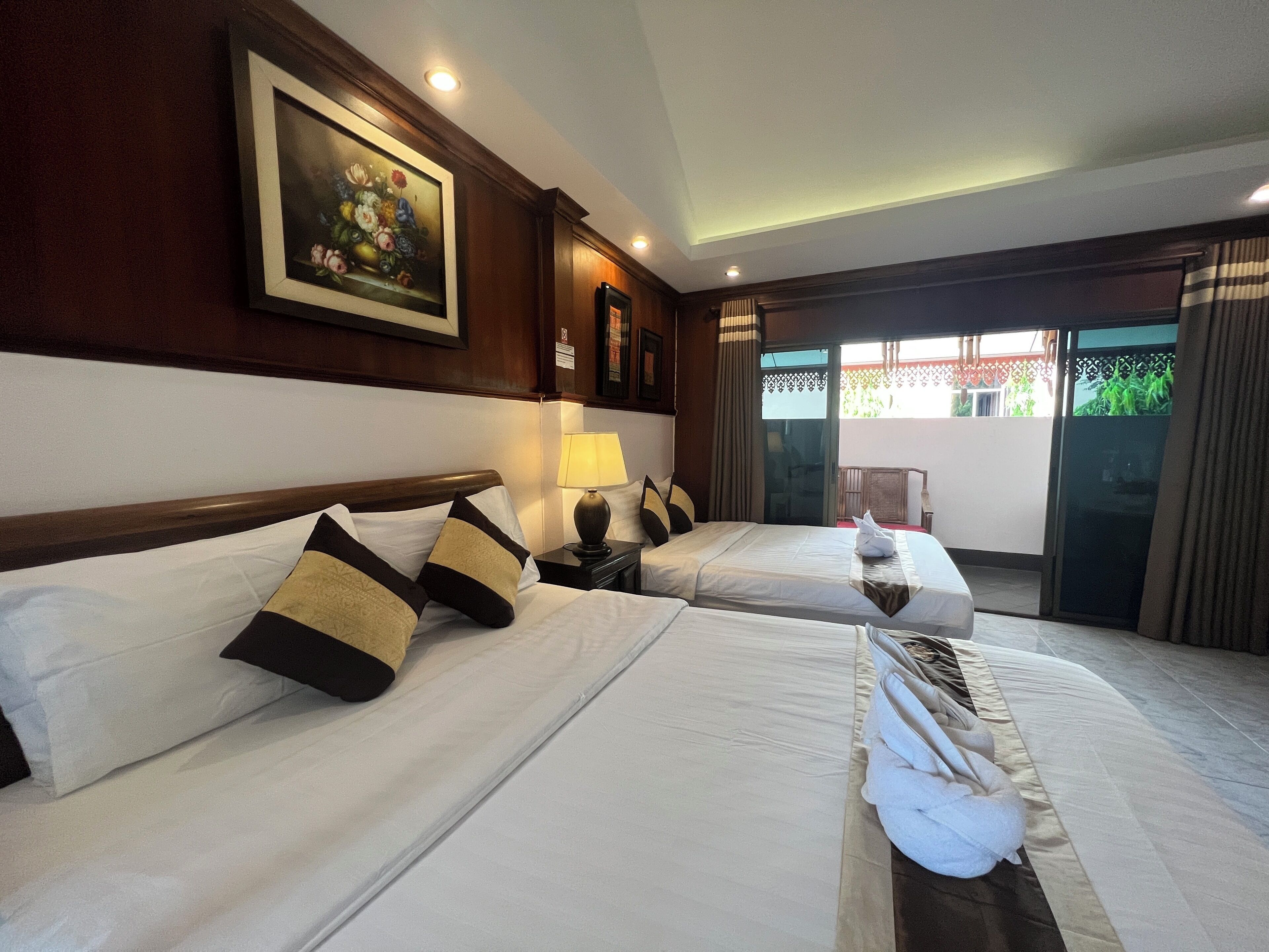 Habitación de hotel con dos camas, un cuadro en la pared, una lámpara en la mesita de noche y vistas al exterior.
