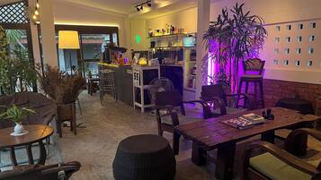 A cozy indoor space with a bar area, seating, and a large potted plant.