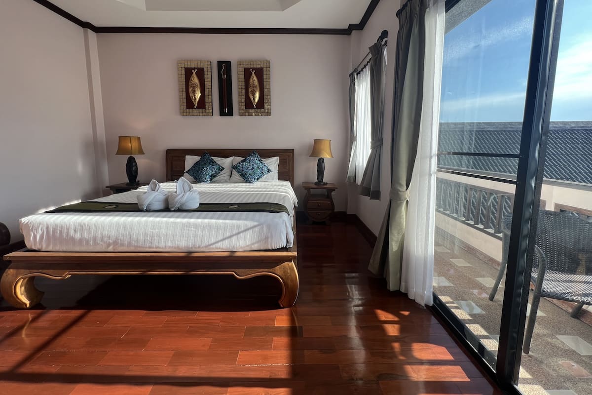 Een ruime slaapkamer met een groot bed, twee bedlampen, uitzicht op het balkon en een plafond met inbouwverlichting.
