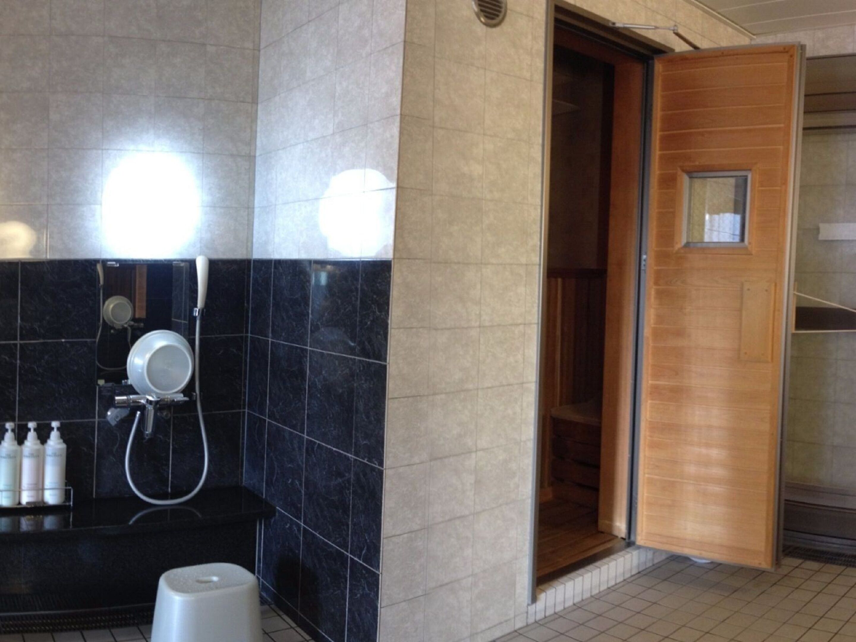 A modern bathroom with a black marble wall, a wooden door, and a shower area.