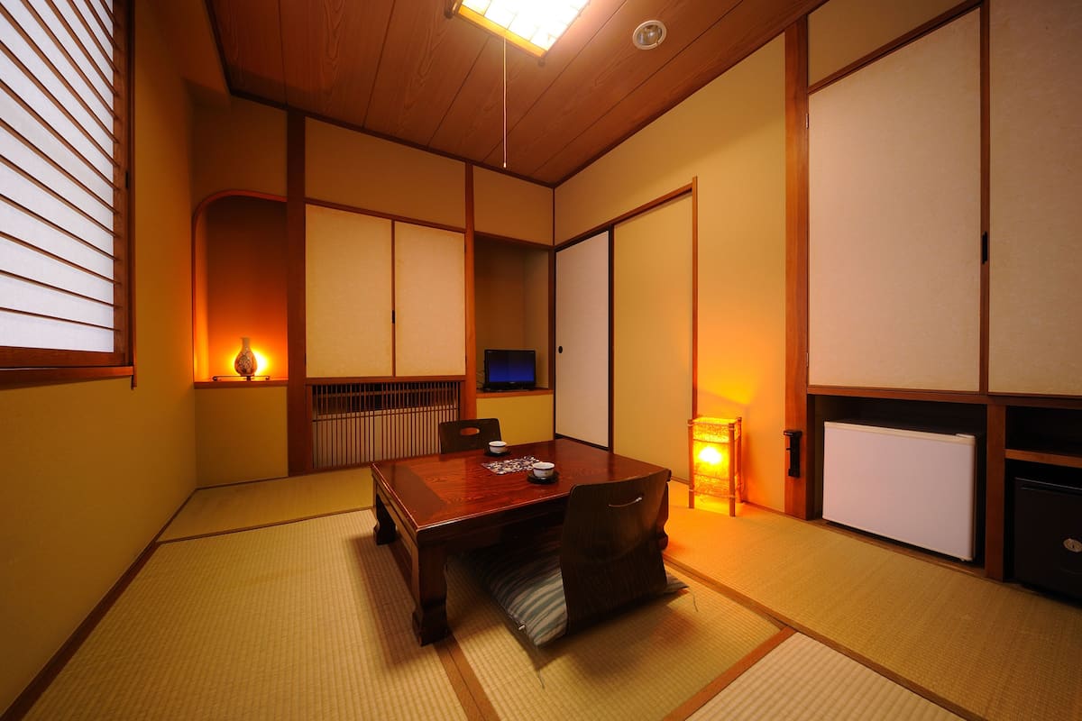 Perinteinen japanilainen huone, jossa on tatamimatto, matala puupöytä, liukuovet ja televisio.