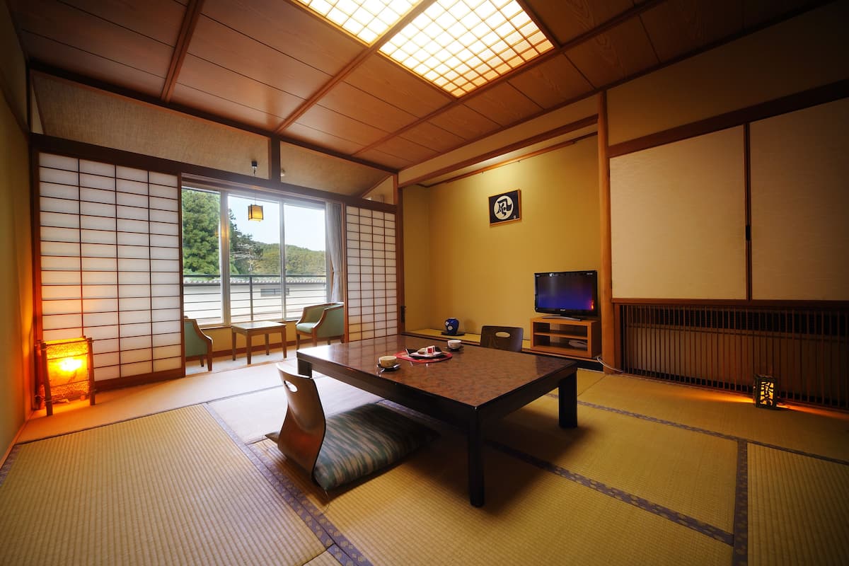 Perinteinen japanilainen huone, jossa on tatamimatto, matala pöytä ja liukuvat ovet.