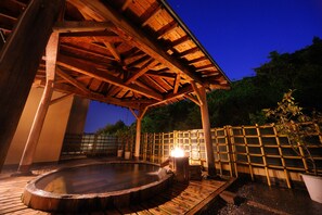 A wooden hot spring bath area with a wooden roof structure and a bamboo fence. - Suzukiya Ryokan (Shiroishi)