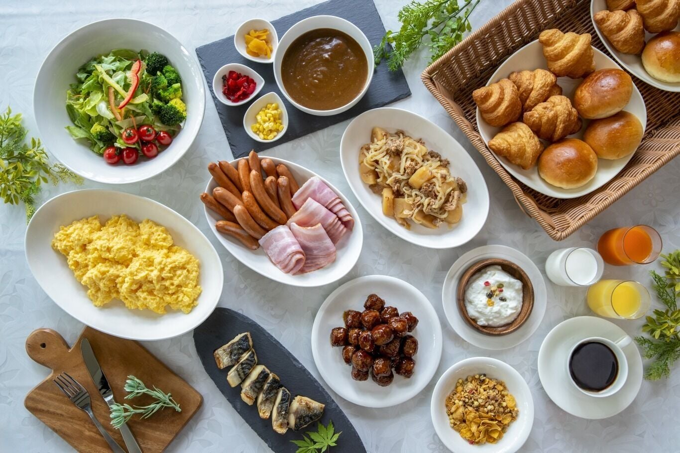 A variety of breakfast items including scrambled eggs, sausages, and pastries.