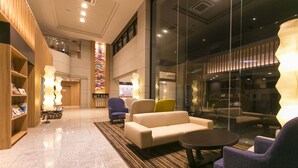 Un hall con un sofá, sillones, una mesita de café y una estantería.
