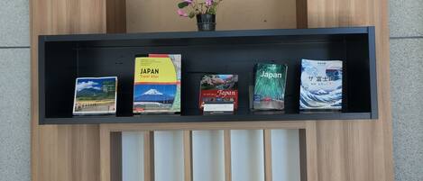 A wooden display with a shelf of travel books and a wall decorated with traditional Japanese fans.