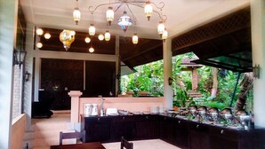 A spacious kitchen with a long counter, hanging pendant lights, and a view of lush greenery outside. - Aonang Cliff Mountain New Resort (Krabi)