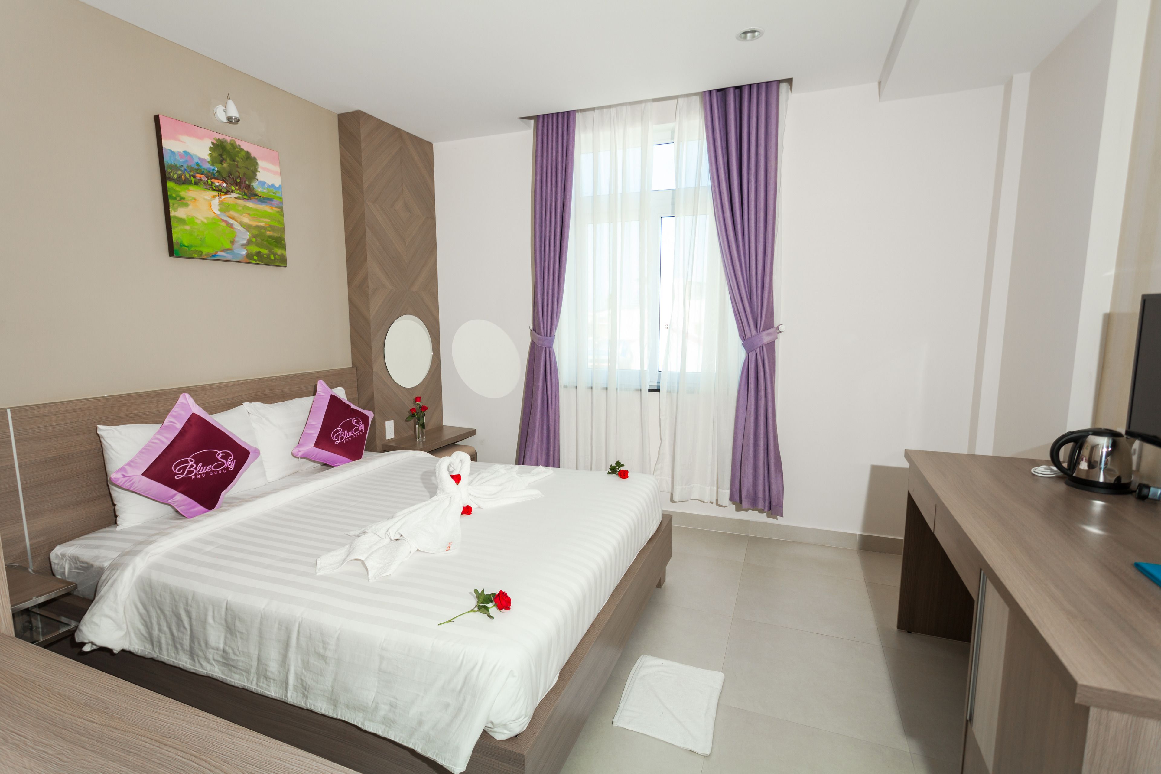 Una camera d'albergo con un letto grande, una scrivania, una televisione e un quadro appeso al muro.